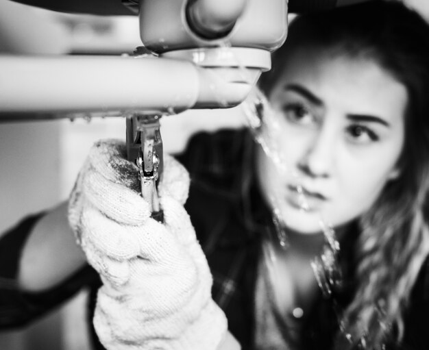 Mujer arreglando el fregadero de la cocina