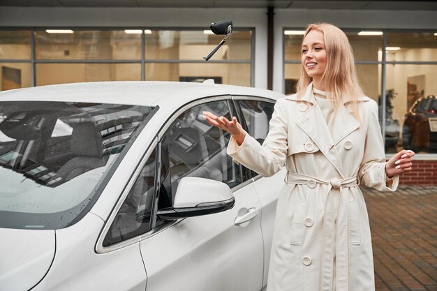 Mujer arrojando las llaves de su auto blanco en el concesionario de autos