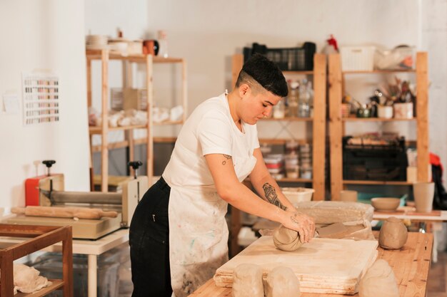 Mujer artesana amasando la arcilla en mesa de madera