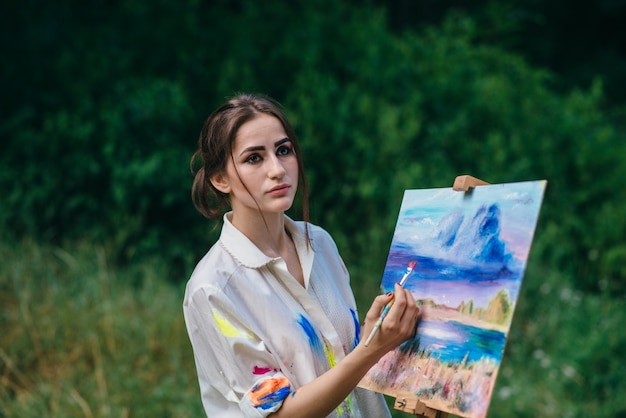 Foto gratuita mujer artista mirando a un lado mientras pinta un cuadro