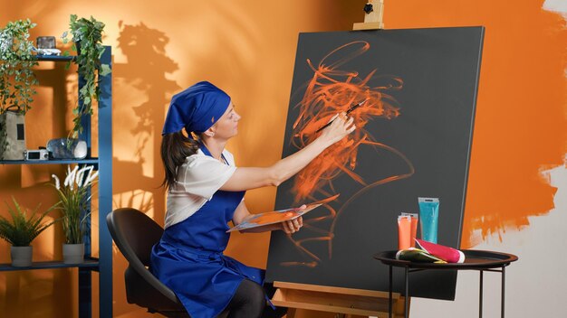 Mujer artista pintando con aquarelle y pincel sobre lienzo, usando paleta de acuarela artística y pincel para crear obras de arte. Hacer obras maestras de arte con habilidades creativas y talento. Disparo de trípode.