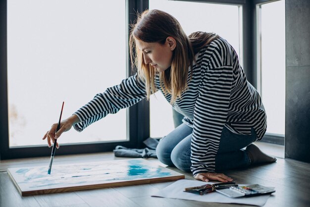 Mujer artista pintando un cuadro en casa