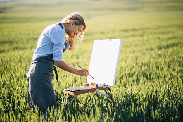 Mujer artista pintando con pinturas al óleo en un campo