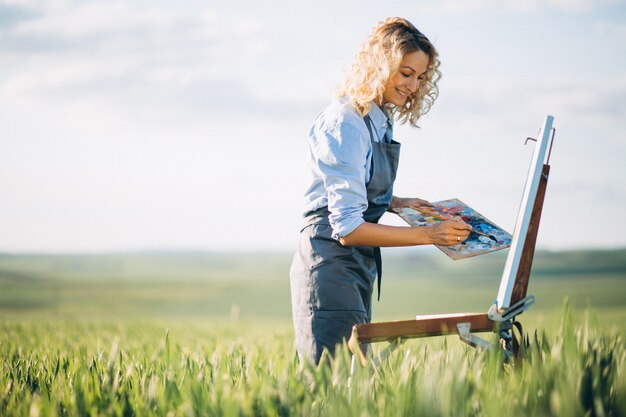 Mujer artista pintando con pinturas al óleo en un campo