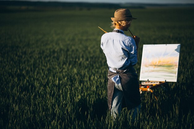 Mujer artista pintando con pinturas al óleo en un campo