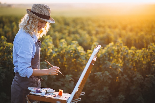 Mujer artista pintando con pinturas al óleo en un campo