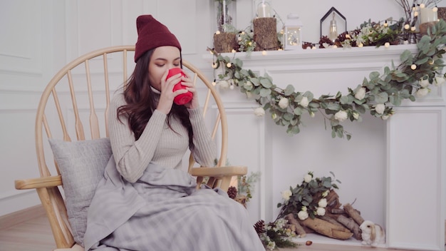 Mujer asiática atractiva hermosa que sostiene una taza caliente de café o de té mientras que miente en silla