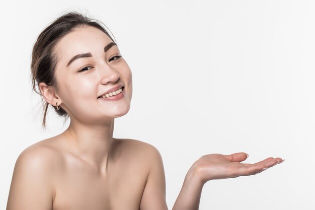 Mujer asiática de la belleza del cuidado de la piel del cuerpo que muestra el producto en lado con la presentación abierta de la mano y exhibición aislada en la pared blanca.