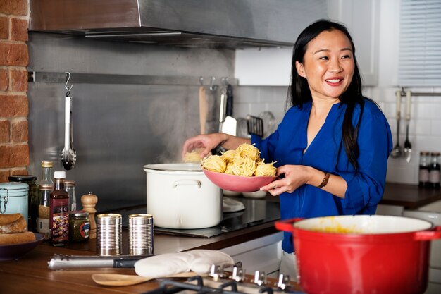Mujer asiática cocinando pasta en la cocina