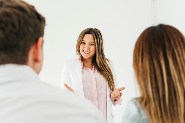 Mujer asiática confiada que hace la presentación para los compañeros de trabajo