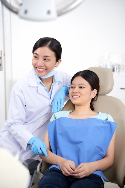 Mujer asiática dentista y paciente sentados juntos y mirando algo