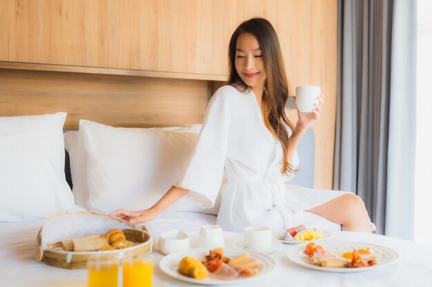 mujer asiática disfrutando con desayuno en la cama