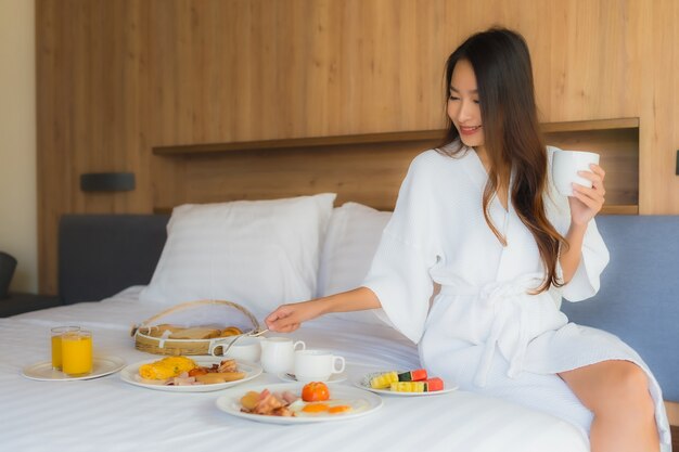 mujer asiática disfrutando con desayuno en la cama