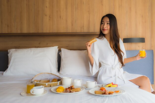 mujer asiática disfrutando con desayuno en la cama