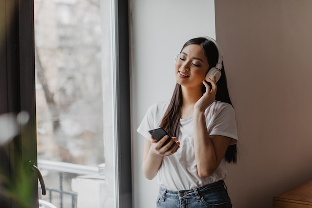 Mujer asiática disfrutando de la música en auriculares con los ojos cerrados