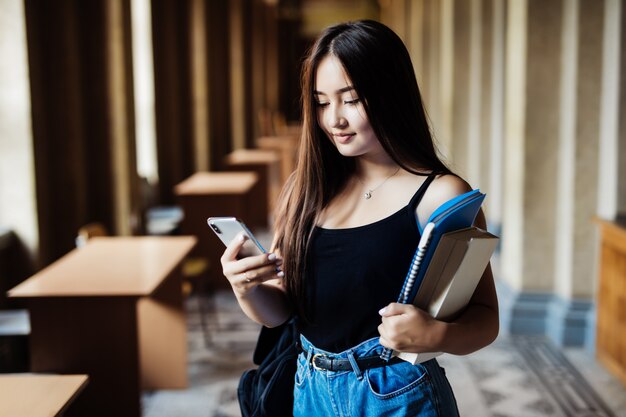 Mujer asiática enviando sms por celular en campus universitario