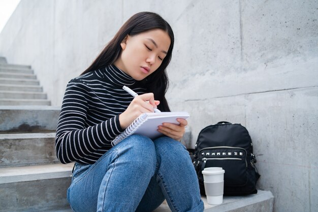 Mujer asiática escribiendo en el cuaderno.