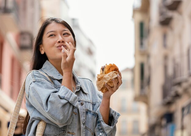 Mujer asiática feliz después de comprar comida en la calle