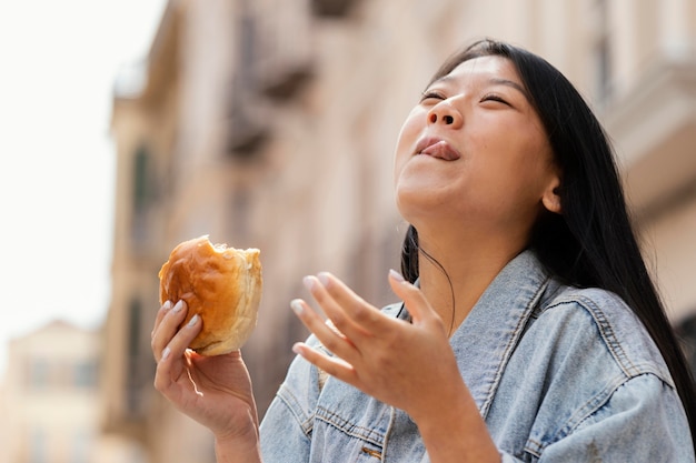 Mujer asiática feliz después de comprar comida en la calle