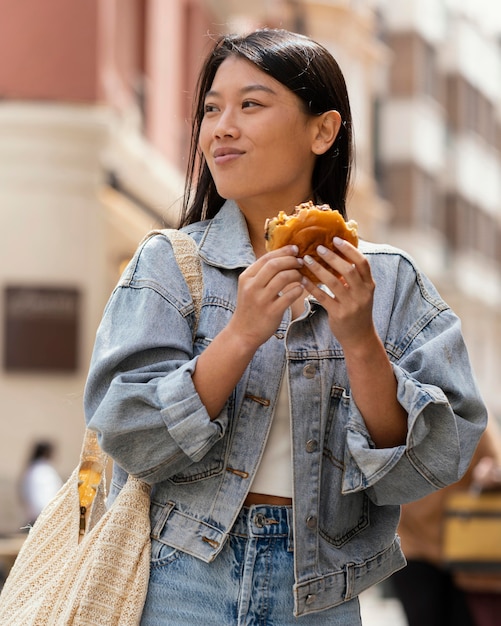 Foto gratuita mujer asiática feliz después de comprar comida en la calle