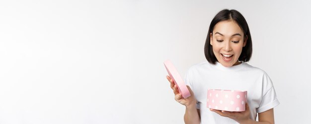 Mujer asiática feliz novia caja abierta con regalo del día de san valentín recibir regalo romántico de pie sobre...