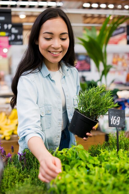 Mujer asiática feliz que elige el verdor en colmado