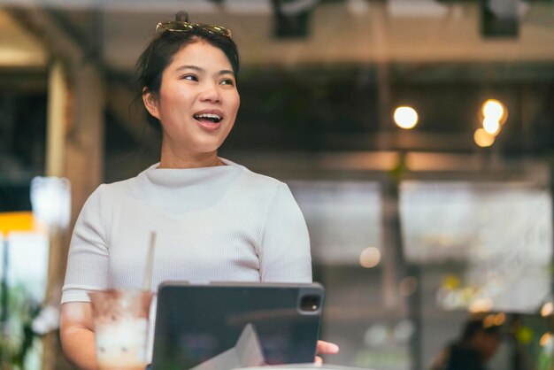 Mujer asiática freelance digital nómada carrera felicidad trabajo alegre sonriente trabajando en línea con dispositivo inteligente tableta teléfono inteligente ocupación en el extranjero proyecto trabajo en cualquier lugar nuevo estilo de vida sin marco