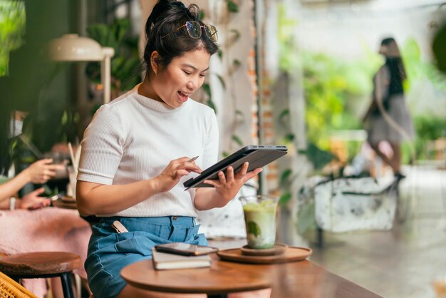 Mujer asiática freelance digital nómada carrera felicidad trabajo alegre sonriente trabajando en línea con dispositivo inteligente tableta teléfono inteligente ocupación en el extranjero proyecto trabajo en cualquier lugar nuevo estilo de vida sin marco