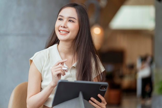 Mujer asiática freelance digital nómada carrera felicidad trabajo alegre sonriente trabajando en línea con dispositivo inteligente tableta teléfono inteligente ocupación en el extranjero proyecto trabajo en cualquier lugar nuevo estilo de vida sin marco