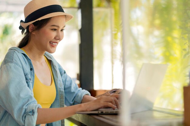 Mujer asiática freelance nómada digital millennial gen y estilo de vida relajarse informal trabajando con una computadora portátil al aire libre en el balcón cerca de la playa mujer asiática trabajando en cualquier lugar nuevo estilo de vida trabajando mientras viaja