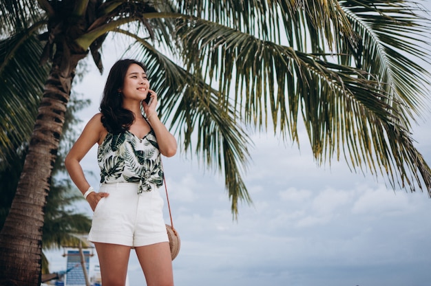 Foto gratuita mujer asiática hablando por teléfono en la playa