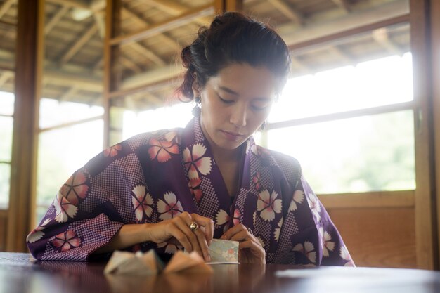 Mujer asiática haciendo origami con papel japonés