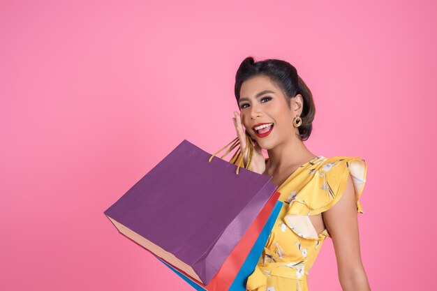 Mujer asiática hermosa que sostiene bolsos de compras coloreados