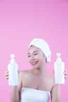 Foto gratuita mujer asiática hermosa que sostiene una botella de producto en un fondo rosado.