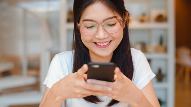 Mujer asiática independiente mediante teléfono móvil en la oficina