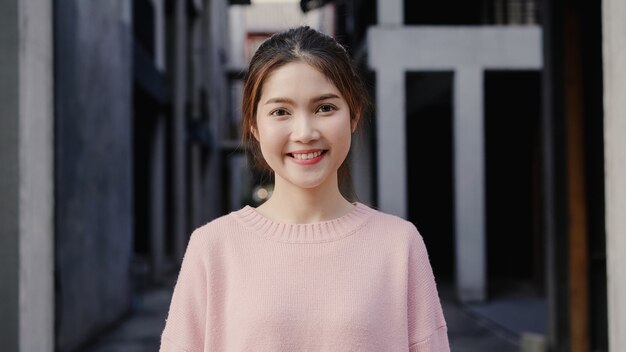 Mujer asiática joven hermosa alegre que siente la sonrisa feliz a la cámara mientras que viaja en Chinatown en Pekín, China.