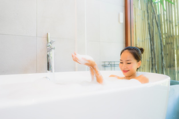 La mujer asiática joven hermosa del retrato en la bañera para toma un baño