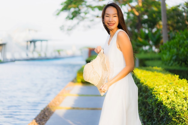 Mujer asiática joven hermosa del retrato feliz y sonrisa en el mar y el océano de la playa