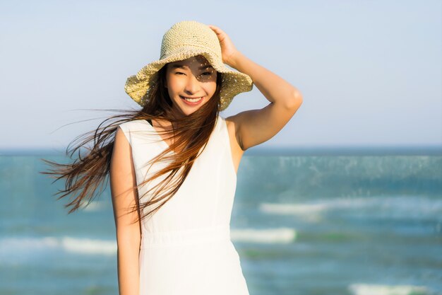 Mujer asiática joven hermosa del retrato feliz y sonrisa en el mar y el océano de la playa