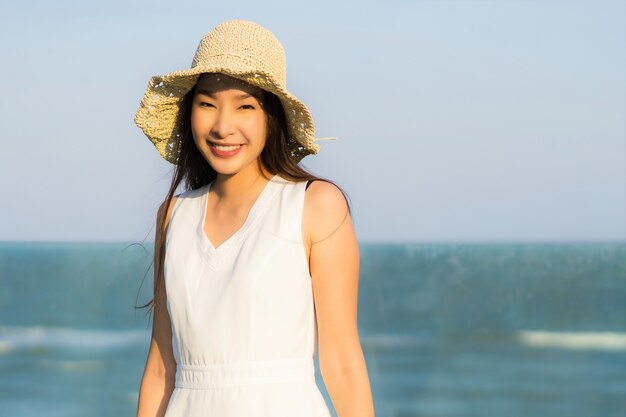 Mujer asiática joven hermosa del retrato feliz y sonrisa en el mar y el océano de la playa