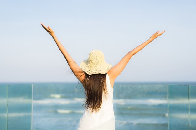 Mujer asiática joven hermosa del retrato feliz y sonrisa en el mar y el océano de la playa