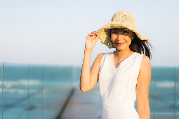 Mujer asiática joven hermosa del retrato feliz y sonrisa en el mar y el océano de la playa