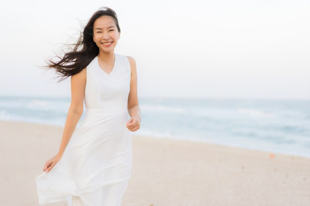 Mujer asiática joven hermosa del retrato feliz y sonrisa en el mar y el océano de la playa