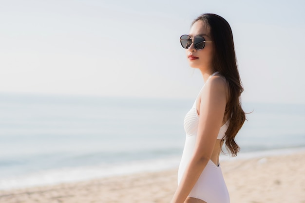 Mujer asiática joven hermosa del retrato feliz y sonrisa en el mar y el océano de la playa