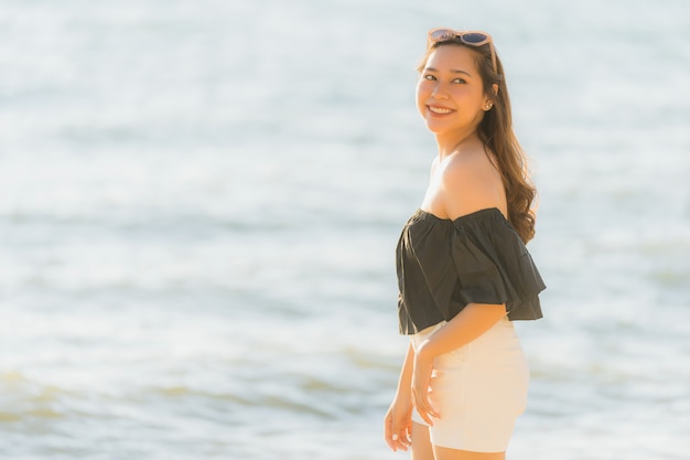 Mujer asiática joven hermosa del retrato feliz y sonrisa en el mar y el océano de la playa