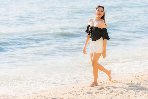 Mujer asiática joven hermosa del retrato feliz y sonrisa en el mar y el océano de la playa