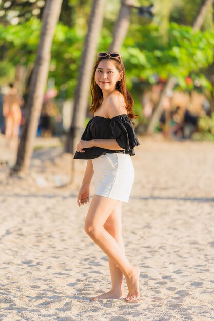 Mujer asiática joven hermosa del retrato feliz y sonrisa en el mar y el océano de la playa