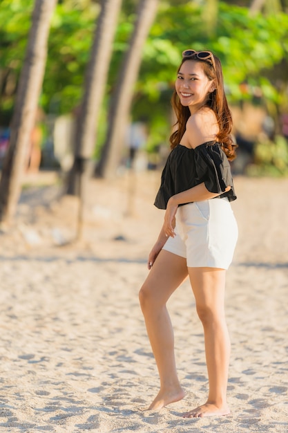 Mujer asiática joven hermosa del retrato feliz y sonrisa en el mar y el océano de la playa