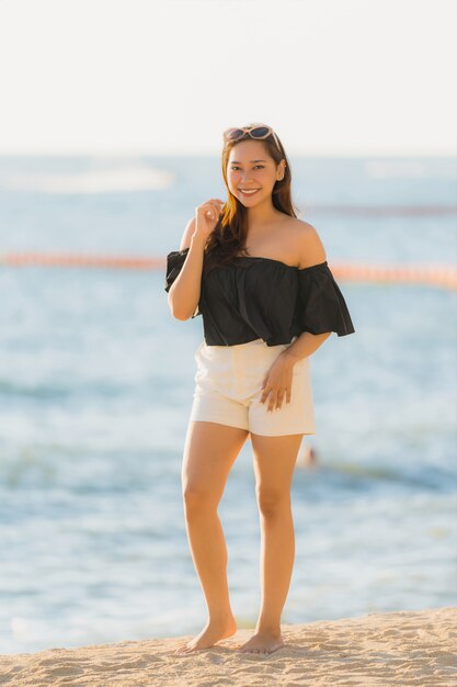 Mujer asiática joven hermosa del retrato feliz y sonrisa en el mar y el océano de la playa