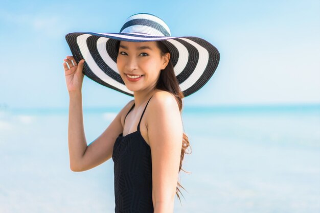 Mujer asiática joven hermosa del retrato feliz y sonrisa en la playa y el mar